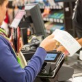 Caucasian woman electronic signing her bill at the supermarket