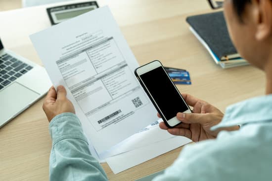 A male businessman using a smart phone to scan a barcode to pay monthly phone bills after receiving invoices. Online bill payment concept